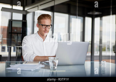 Businessman using laptop on desk in office Banque D'Images