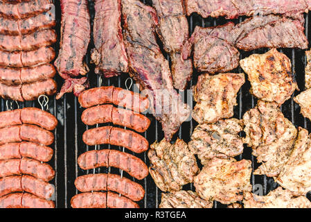 Saucisses, porc et poulet rôti sur un barbecue, vu de dessus. Banque D'Images