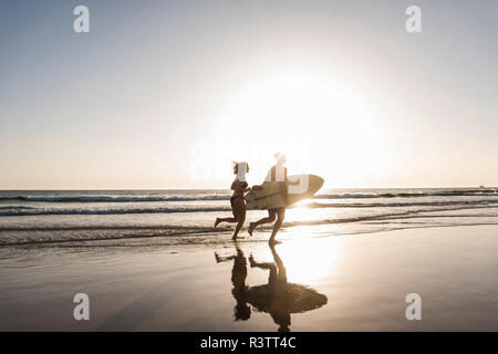 Jeune couple d'exécution sur plage, surf Transport