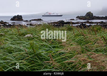 Archipel des Aléoutiennes, Alaska, magnitude 5,2 dans. L'Île Seguam distant, paysage volcanique avec navire d'expédition de Silversea, découvreur d'argent. Banque D'Images