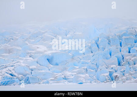 USA, Alaska. Le visage de l'Mendenhall Glacier émerge des nuages qu'il rencontre la lac Mendenhall congelé. Banque D'Images