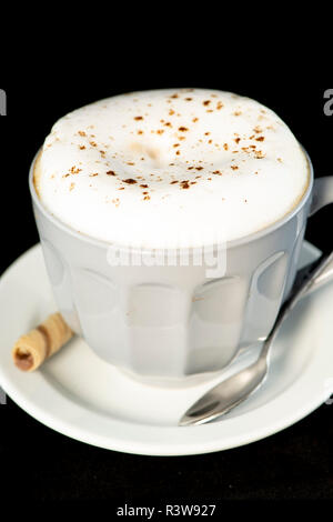 De délicieux cappuccino servi avec plaquette chocolat noisette isolées rouleaux fond noir Banque D'Images