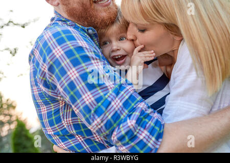 Heureux parents hugging her daughter outdoors Banque D'Images