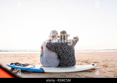 Couple camping sur la plage, en tenant vos autoportraits smartphone Banque D'Images