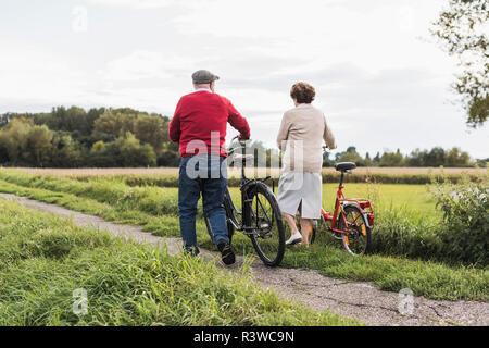 Senior couple poussant les vélos in rural landscape Banque D'Images