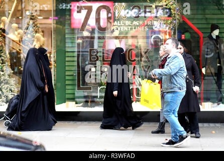 Pic montre : le Black Friday sales trois femmes musulmanes en pleine burqas contre ont été appréciant les ventes. Les acheteurs ont été en grande partie underwhelmed aujourd'autour de Oxford Stre Banque D'Images