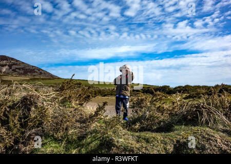 Jeune garçon sous un ciel bleu avec des nuages blancs sur un jour lumineux en face de la montagne Sugarloaf dans le comté de Wicklow, Irlande de l'ouest bordant le norther Banque D'Images