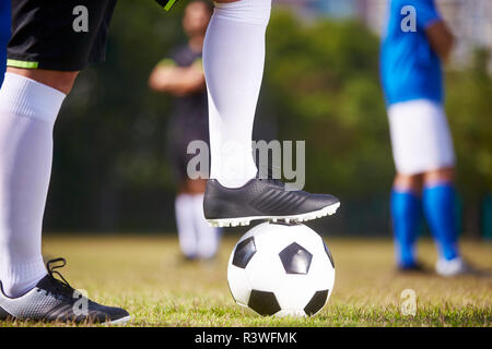 Pied d'un joueur de foot en marchant sur un ballon de football prêt à donner le coup d'un match Banque D'Images