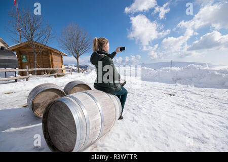 Femme blonde assis sur des tonneaux de bois photographies les paysages enneigés. Banque D'Images