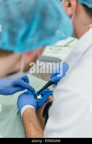 Médecin utilisé microscope. Dentiste est de traiter le patient en cabinet dentaire moderne. L'opération est réalisée à l'aide de batardeau. Client est inséré et restauré Banque D'Images