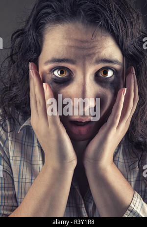 Close-up of a young woman with peur normale yeux tachés sur fond gris Banque D'Images