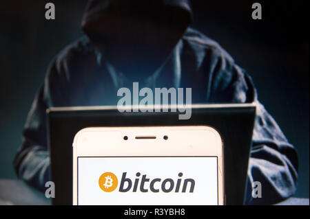 Hong Kong. 22 Nov, 2018. L'argent électronique Cryptocurrency logo Bitcoin est vu sur un appareil mobile Android avec une figure de hacker dans l'arrière-plan. Credit : Miguel Candela/SOPA Images/ZUMA/Alamy Fil Live News Banque D'Images