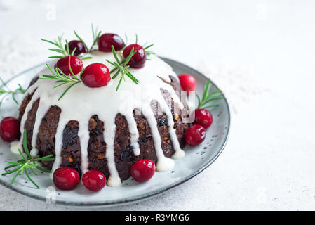 Le pudding de Noël, fruits gâteau décoré avec du glaçage et des canneberges sur tableau blanc, Close up. Le dessert traditionnel de Noël fait maison - Noël Puddin Banque D'Images