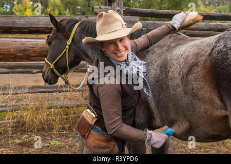 USA, Montana, E/L Ranch. Cowgirl cheval de toilettage. En tant que crédit : Marie Bush / Jaynes Gallery / DanitaDelimont.com (MR) Banque D'Images