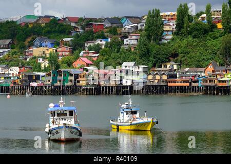 L'ancrage des bateaux de pêche colorés en face de maisons sur pilotis, pile dwellings, appelées palafitos, Castro, île de Chiloé, Chili Banque D'Images