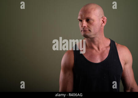 Bald man wearing tank top musclé contre l'arrière-plan de couleur Banque D'Images