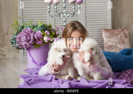 Portrait de dame blonde fille jouant avec husky poppy.Model girl aux cheveux blonds posant en studio shoot avec Sammy chiot blanc tandis que se trouvent sur sol en bois cheminée Banque D'Images