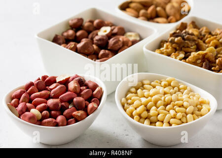 Diverses noix dans un bol en céramique (noix, amandes, noisettes, noix de pin) sur une table en pierre. Le concept d'un dessert sain. Banque D'Images
