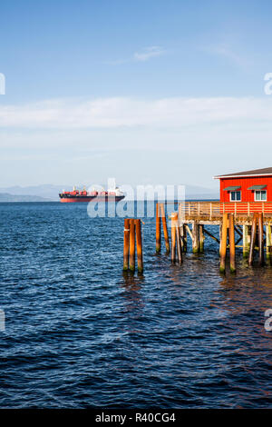 Astoria, Oregon. Conteneurs rouge, bâtiment et un dock avec les pilotis sur le fleuve Columbia Banque D'Images