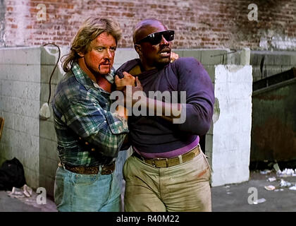 Frank (Keith David) essaie sur le Hoffman des lentilles pour la première fois, à partir de la ils vivent (1988) réalisé par John Carpenter. Un drifter trouve une paire de lunettes de soleil qui révèlent la vérité du monde et comment il manipule et récompense ses habitants. Banque D'Images