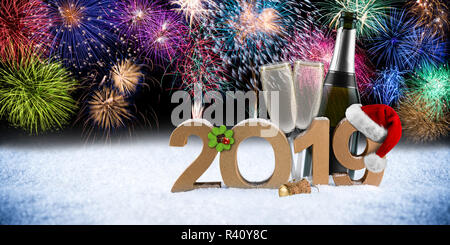 Bonne année 2019 nombre with santa hat trèfle à quatre feuilles de verre bouteille de champagne en face d'artifice coloré fond neige panorama pyrotechnique Banque D'Images