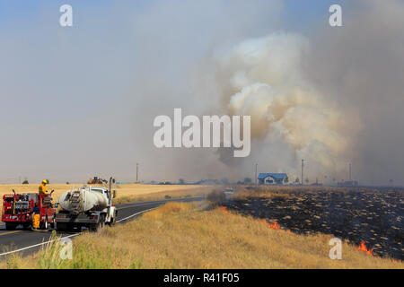 Walla Walla, Washington State, USA. Le personnel de lutte contre l'incendie du comté de travailler d'éteindre un petit feu de brousse. Banque D'Images