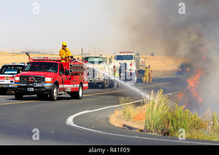 Walla Walla, Washington State, USA. Le personnel de lutte contre l'incendie du comté de travailler d'éteindre un petit feu de brousse. Banque D'Images