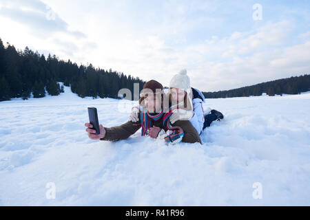 Couple romantique s'amuser dans la neige et prendre selfies Banque D'Images