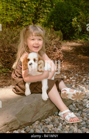 Issaquah, Washington State, USA. Fillette de trois ans la tenue d'une 15 semaine vieux Cavalier King Charles Spaniel puppy. (PR,MR) Banque D'Images