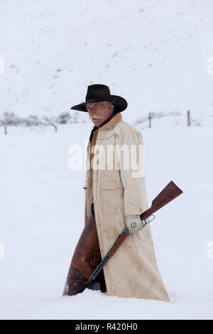 Cowboy tenant son fusil en hiver, Hideout Ranch, Shell, Wyoming. (MR, communication) Banque D'Images