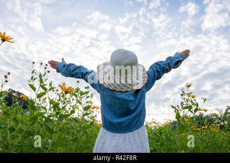 Les enfants dans le champ de fleurs jaune jaune. Dutch girl in white hat Banque D'Images