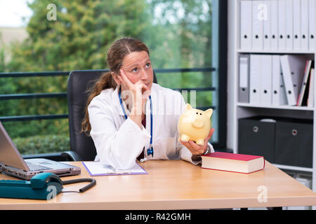 Young female doctor with piggybank Banque D'Images