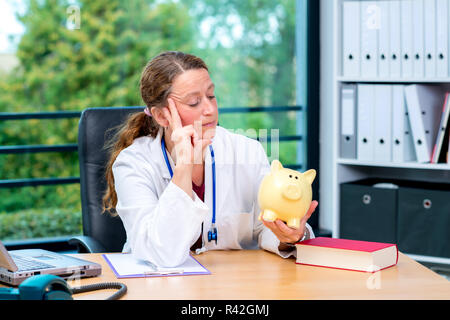 Young female doctor with piggybank Banque D'Images