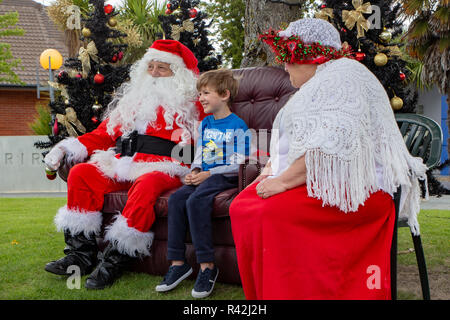 Rangiora, Nouvelle-Zélande - 23 novembre 2018 : Père et Mère Noël écouter un voeux de Noël de l'enfant à la fête du village de Noël Banque D'Images