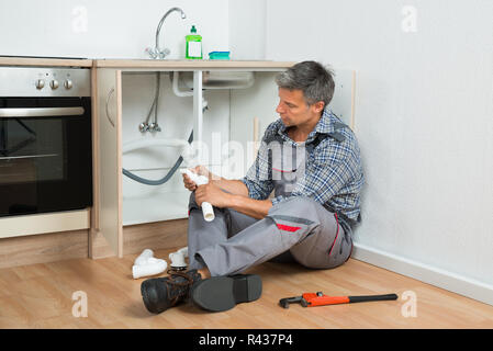 Plumber Repairing Sink pipe dans la cuisine Banque D'Images