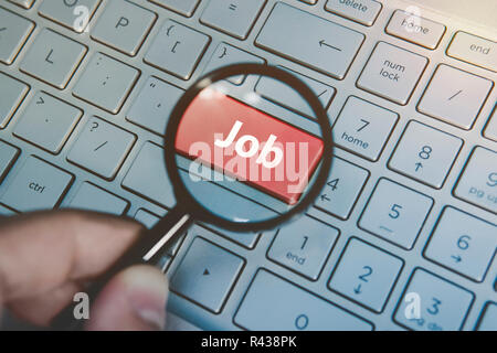 Amplifiés par le bouton loupe sur le clavier d'un ordinateur portable. L'homme utilise une loupe pour agrandir clé travail sur ordinateur numérique. Concept de la recherche d'emploi en ligne. Le surf internet pour trouver de l'occupation Banque D'Images