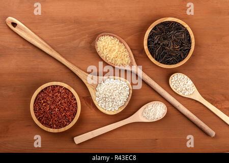 Grain de riz long rouge de Camargue, riz blanc paella bomba, risotto carnaroli, étuvé, jasmin, et riz noir sauvage, tourné par le haut sur une sombre rustic Banque D'Images