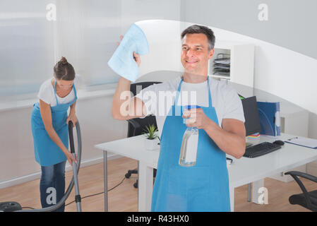 Travailleur homme Nettoyage vitre tout en travailleur féminin l'aspirateur Banque D'Images