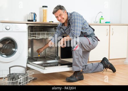 Réparation réparateur lave-vaisselle à l'aide d'un tournevis dans la cuisine Banque D'Images