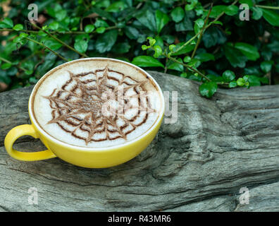 Tasse de café latte en bois avec verre sur fond de feuilles vertes. Banque D'Images