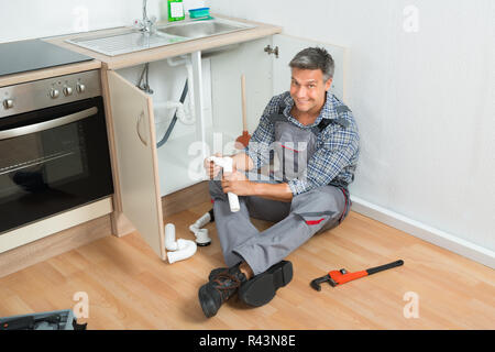 Plumber Repairing Sink pipe dans la cuisine Banque D'Images