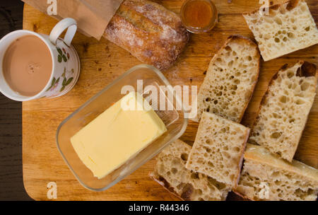 Le petit-déjeuner avec du pain type baguette française, confiture et thé, sur une planche en bois vertical, vue d'en haut Banque D'Images