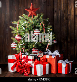 Arbre de Noël décoré avec des cannes de bonbon , star , boules rayées et coffrets cadeaux sur fond de bois Banque D'Images