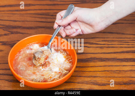 Main courante cuillère à soupe aux choux sur bol Banque D'Images