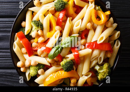 L'Italien pâtes penne avec pois chiches, légumes, herbes et épices close-up dans une assiette sur la table. Haut horizontale Vue de dessus Banque D'Images