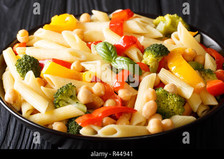 Salade de pâtes penne avec les pois chiches, le brocoli, le poivron et les épices libre dans une assiette sur la table horizontale. Banque D'Images