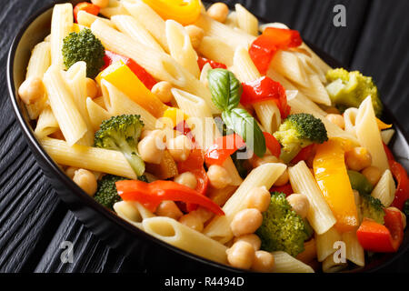 Close-up de l'alph pâtes penne avec les pois chiches, le brocoli, le poivron et les épices dans une assiette sur la table horizontale. Banque D'Images