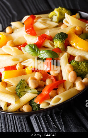 Les délicieux salade de pâtes penne avec pois chiches, brocoli, poivrons libre dans une assiette sur la table. vertical Banque D'Images