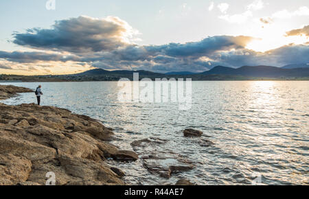 Au bord d'un pêcheur au coucher du soleil à Jindabyne dans l'arrière-plan Banque D'Images