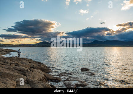 Au bord d'un pêcheur au coucher du soleil à Jindabyne dans l'arrière-plan Banque D'Images